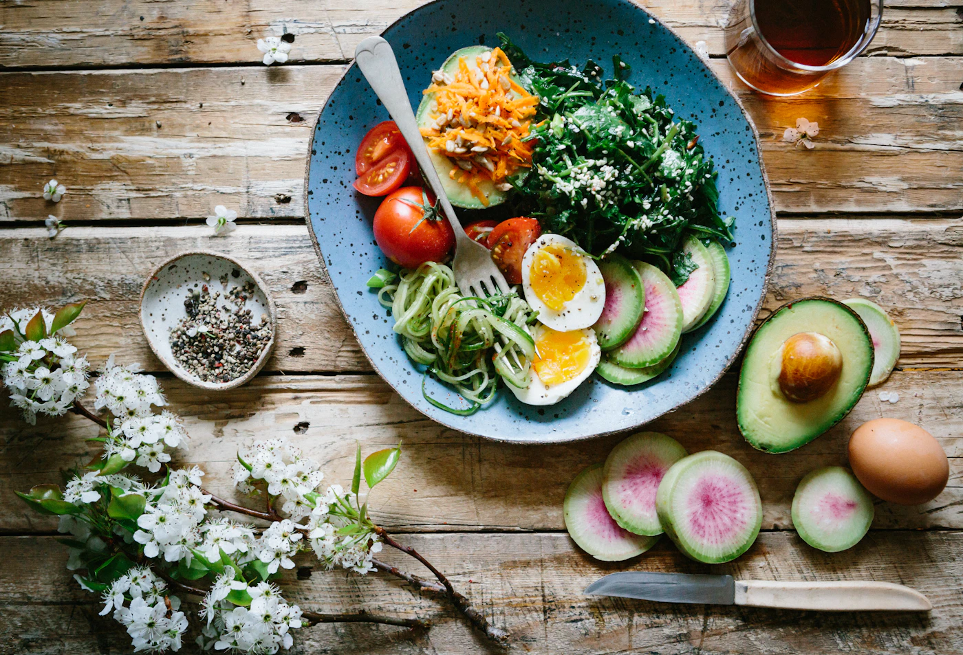 Colourful bowl of fresh seasonal vegetables and grains on a wooden table